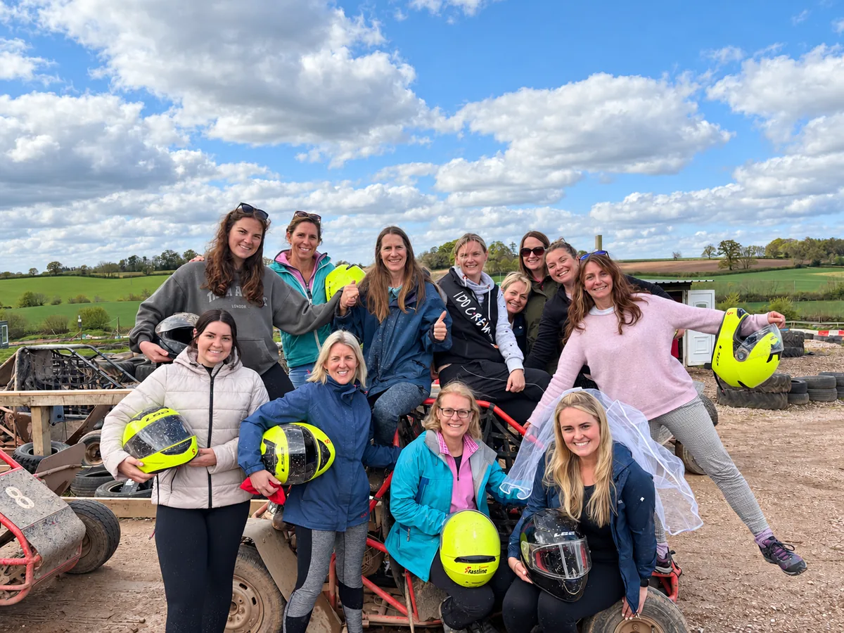 A hen party holding helmets beside the karts at Exeter Karting in Devon