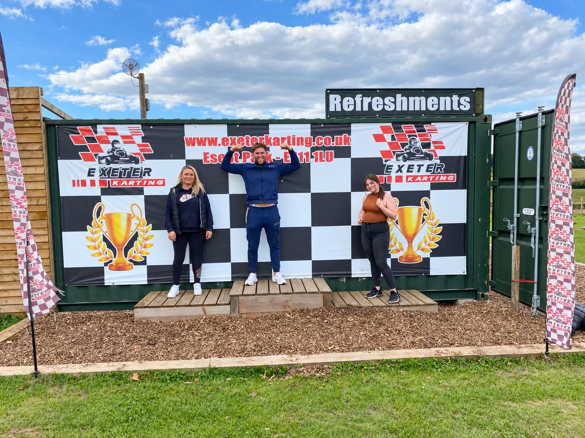 Three visitors celebrating on the Exeter Karting podium after their time trials