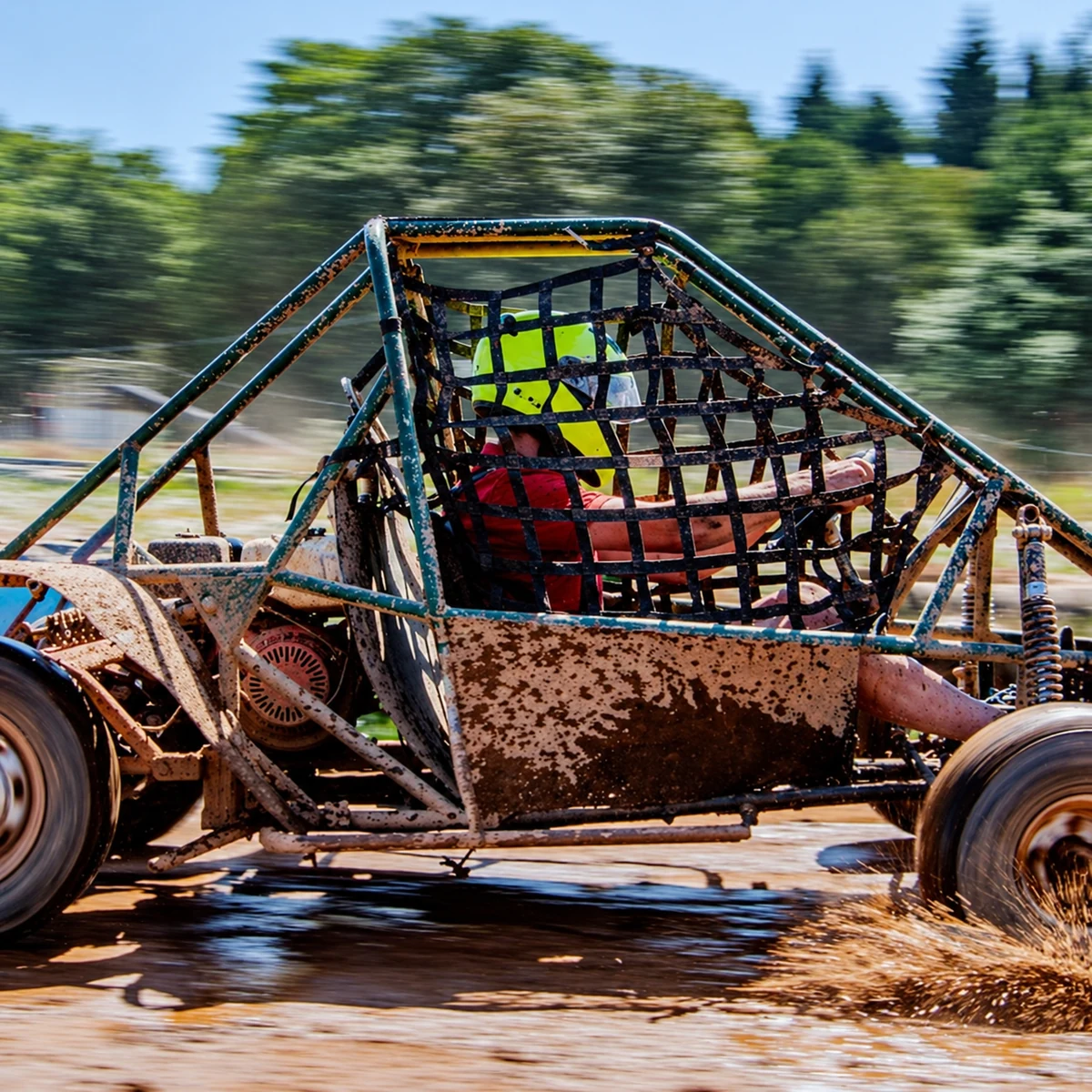 A helmeted driver taking an off-road kart past the tyre barriers